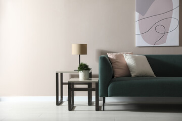 Stylish living room interior with comfortable green sofa and beautiful plant. Space for text
