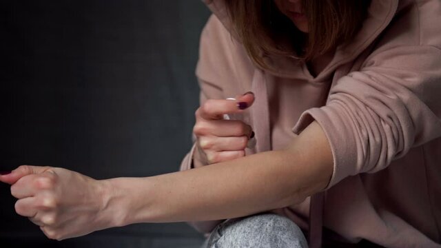 Woman injecting drug into her arm with a syringe.
