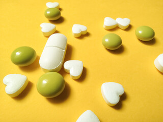 round oval pills with hearts on yellow-orange background
