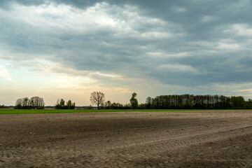 Plowed field and dark storm clouds on the sky