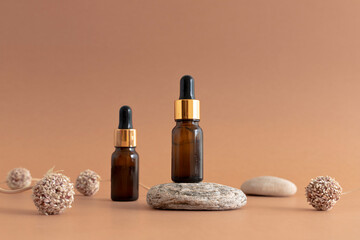 Composition of cosmetic bottles made of dark glass with pipettes with natural elements - stone, grass, dried garlic flowers in the foreground. Natural organic cosmetics concept. 