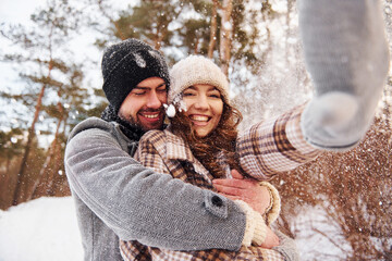 Obraz premium Cheerful couple have a walk in the winter forest at daytime