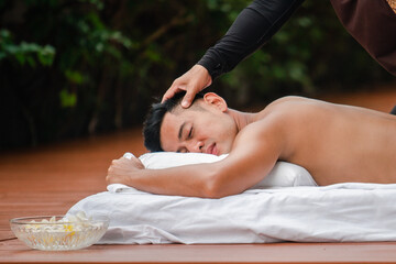 Obraz na płótnie Canvas Asian man enjoy a massage by the resort's pool.
