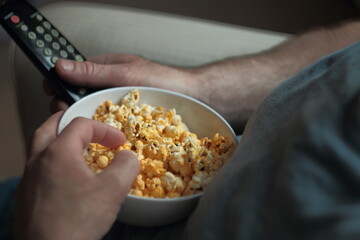 man eating popcorn and watching tv