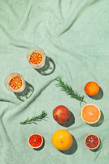 Summer scene with fruits,rosemary and glasses of water or lemonade on pastel green beach towel. Drinks and refreshment concept. Sunlit flat lay. Minimal style. Top view. © Androlia