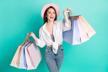 Photo of sweet cute young lady wear white shirt cap smiling holding shopping bags isolated...