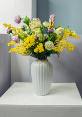 Artificial flowers in a vase on a gray background. Copy space
