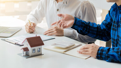 Real estate agents introduce the house style to clients while signing contracts with clipboards at...