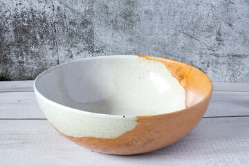 Empty brown handmade ceramic bowl Japanese style on wooden table and dark gray cement background,...