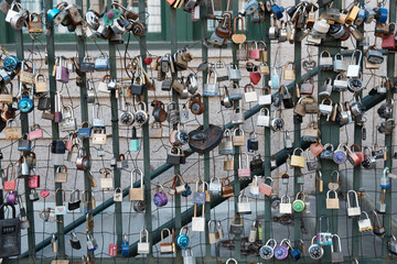 Padlocks attached to a wire fence and metal railing to express love for another person