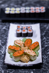 set of sushi rolls with seafood on a black stone background