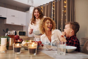 Having a dinner. Happy family of mother, daughter and son is on the kitchen at evening time