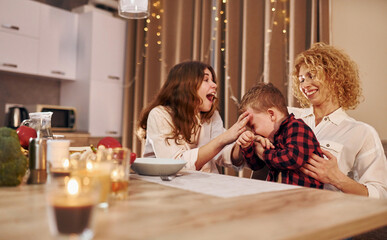 Spending weekend together. Happy family of mother, daughter and son is on the kitchen at evening time