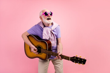 Photo portrait of funky happy grandpa playing guitar wearing star sunglass isolated on pastel pink...