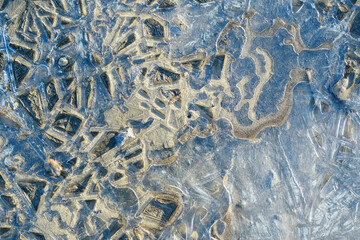 Frozen water and sand. Lines and patterns of ice. Icy abstraction concept.