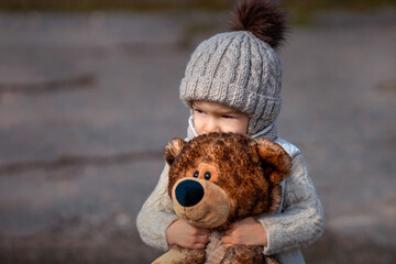 The baby hugs his toy. A little boy and a bear. Emotions. Baby in a knitted hat hugs the toy...