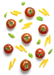 Tubular pasta type, cherry tomatoes and basil leaves arranged on white background.Top view. Mediterranean cuisine ingredients.