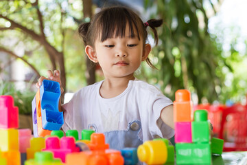 Portrait image of 3-4 toddler kid. Happy Asian child girl playing the plastic block toys. Learning...