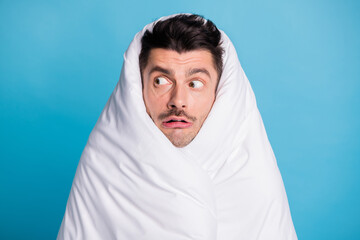 Photo portrait of scared terrified man looking to side wrapped in blanket isolated on vivid blue colored background