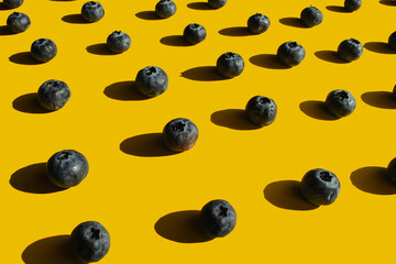 Healthy food, raw food, breakfast. Blueberries in hard harsh light against a bright yellow background. Patern.