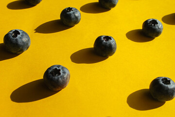 Healthy food, raw food, breakfast. Blueberries in hard harsh light against a bright yellow background.