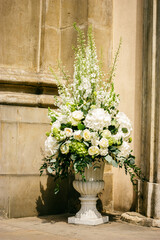 Fototapeta na wymiar Beautiful white flowers in bowl near church door