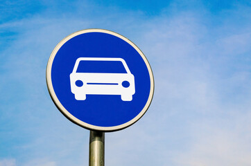 Car blue circular sign. Mandatory road signs with a car. Blue sky background.