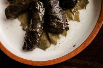 Georgian dish dolma. minced meat in grape leaves on a clay plate with white sauce
