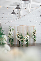 metal gold design with rectangular light bulbs and fresh flowers on a white wall background
