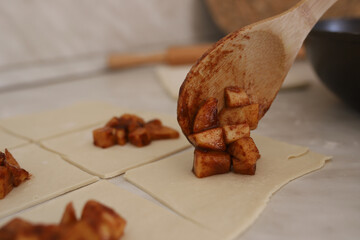 Spreading the apple and cinnamon filling onto the cut dough. Homemade baked goods with filling.