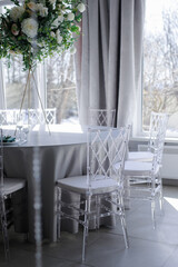 transparent plastic chairs at a round table with a blue tablecloth indoors