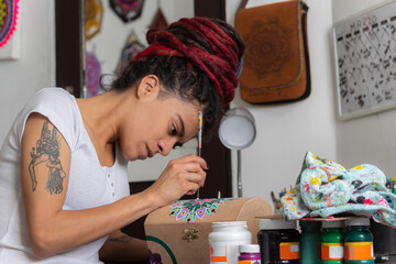 woman sitting with dreadlocks making handcrafts at home