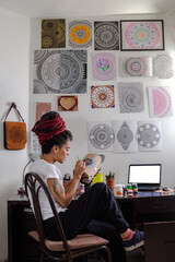 woman sitting with dreadlocks making handcrafts at home