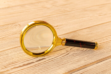 A magnifying glass on a wooden table. The concept of information search. Selective focus.