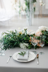 serving on the table of the newlyweds. White plate with glasses and utensils on the background of a blue tablecloth