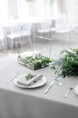 serving on the table of the newlyweds. White plate with glasses and utensils on the background of a blue tablecloth