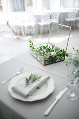serving on the table of the newlyweds. White plate with glasses and utensils on the background of a blue tablecloth