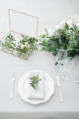 serving on the table of the newlyweds. White plate with glasses and utensils on the background of a blue tablecloth