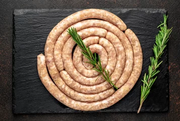 Poster raw spiral chicken sausages with ingredients on stone background © александр таланцев