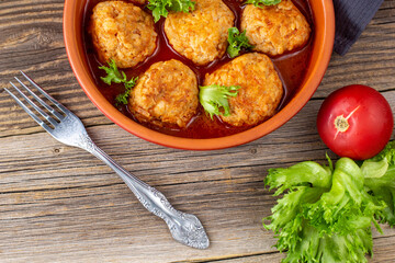 Meatballs in tomato sauce in a bowl on wooden table.