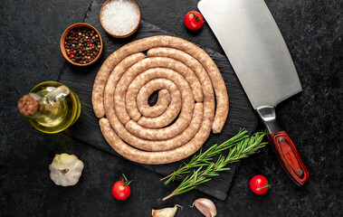 raw spiral chicken sausages with ingredients on stone background