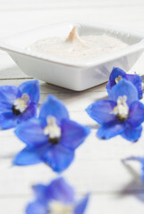 Obraz na płótnie Canvas Cosmetic cream and blue flower