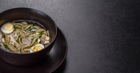 Fresh delicious hot soup with noodles and quail egg in a black plate