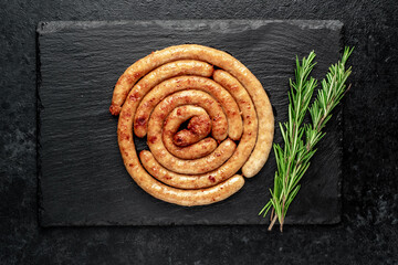 grilled chicken sausages in spiral shape with ingredients on stone background