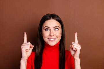 Photo of pretty positive lady look interested direct fingers up empty space isolated on brown color...