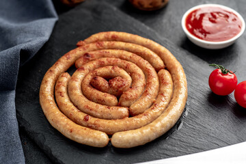 grilled chicken sausages in spiral shape with ingredients on stone background