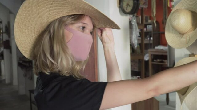 blonde hair mask woman taking selfies trying on cowboy hat in rustic shop