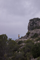 Woman from afar with a yellow jacket on top of a mountain with cloudy weather