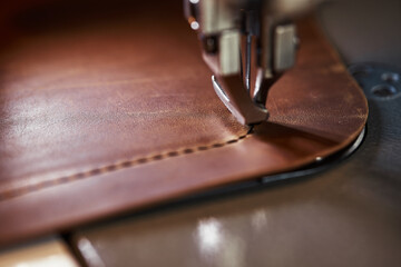 Working process of leather craftsman. Tanner or skinner sews leather on a special sewing machine,...
