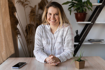 Girl reading sms on line in a smart phone sitting in a table at home with a warm light from a...